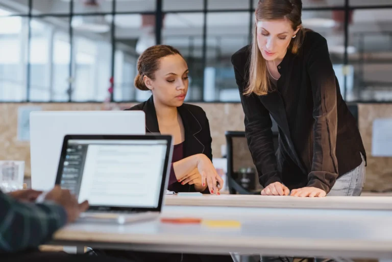 Two business professionals in an office reviewing paperwork to avoid business insurance mistakes.